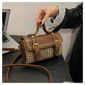 Close-up of retro houndstooth pattern fabric with brown leather stitching and gold buckle