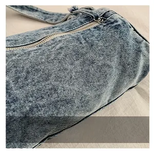 Détail du tissu denim bleu clair et de la fermeture éclair métallique du petit sac
