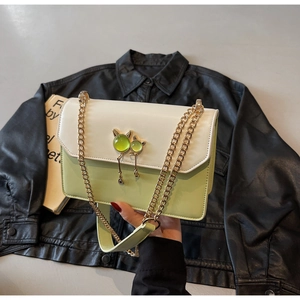 Détail de sac bandoulière avec boucle chat dorée et insert de pierre verte