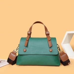 Minimalist green lychee grain leather handbag with brown handles and wide woven strap