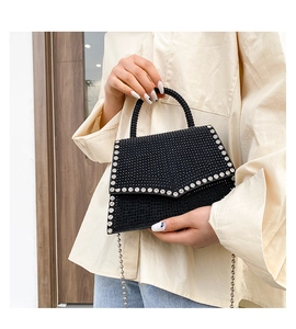 Detail of black rhinestone flap bag with silver rivets and beaded top handle accessory