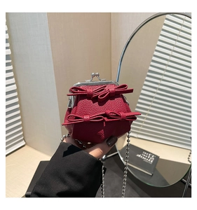 Detail of burgundy mini kiss-lock bag with 3D leather bows and silver ball chain