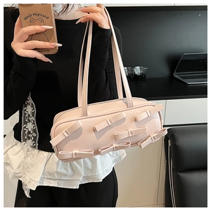 Detail of light pink patent leather handbag with decorative 3D bows and double shoulder straps