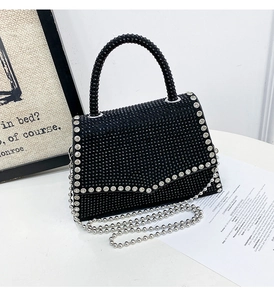 Macro detail of black crystal evening bag with silver chain and white rhinestone accents
