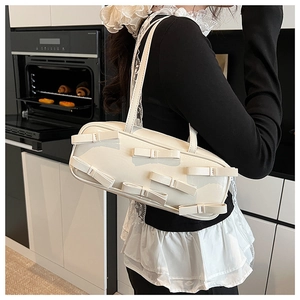 Detailed view of cream-white bow shoulder bag with glossy patent finish and slim straps