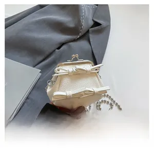 Detail der weißen Mini-Tasche mit Lychee-Muster, Doppel-Schleifen und Kussverschluss
