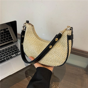 Straw hobo shoulder bag with black leather trim and golden rivets in a daily scene