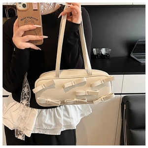 Chic cream bow shoulder bag in shiny faux leather shown in a lifestyle mirror selfie