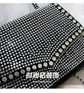 Detailed close-up of sparkling rhinestones on an elegant black crossbody party bag