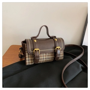 Close-up of retro houndstooth small square bag with leather straps and gold metal buckles