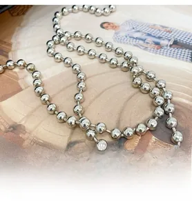 Close-up of a silver polished metal bead chain shoulder strap on a fashion magazine