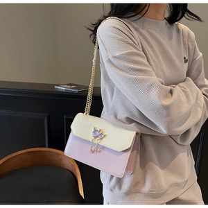 Détail du fermoir chat élégant avec pompons dorés sur le sac à bandoulière chic