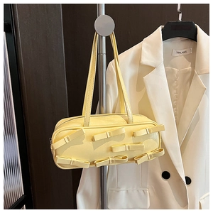Detail of pale yellow patent leather handbag featuring six decorative bows on the front