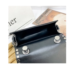 Top view of open black leather crossbody bag with silver rivets and interior space