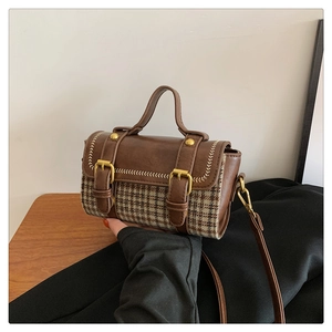 Close-up of vintage houndstooth handbag with brown leather trim and gold buckles