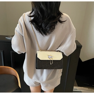 Détail du sac bandoulière pailleté avec fermoir chat en métal et chaîne dorée