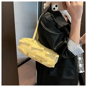 Close-up of yellow rectangular shoulder bag featuring multi-bow details and textured finish