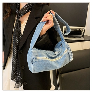 Détail d'un sac tonneau en denim bleu avec fermeture éclair et bandoulière large