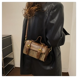 Detail of vintage houndstooth handbag featuring brown leather straps and metal buckle