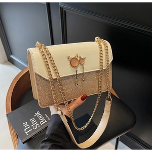 Détail du sac à chaîne en cuir crème avec paillettes dorées et boucles en forme de chat