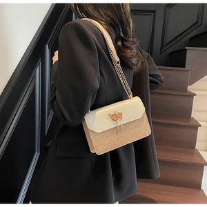 Détail d'un sac à bandoulière élégant avec boucle chat et tissu à paillettes dorées