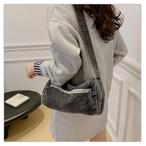 Détail d'un sac cylindrique en denim gris foncé vintage porté par un mannequin