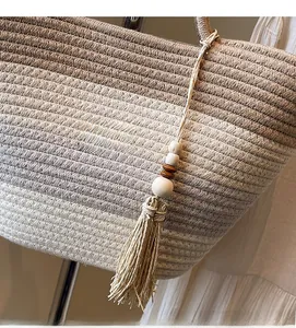 Detail of gradient straw tote bag featuring a wooden bead and beige tassel pendant