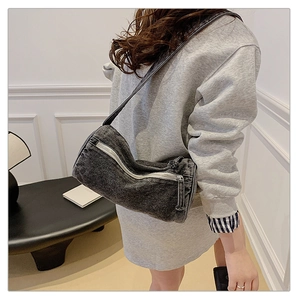 Vue latérale d'un sac cylindrique en denim gris anthracite porté en bandoulière par un mannequin