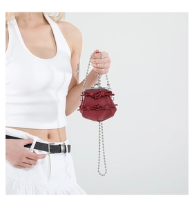 Close-up of red mini bag with bow detail, retro metal lock and silver ball chain strap