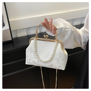 Detail of white jacquard fabric purse with pearl handle and golden metal clasp