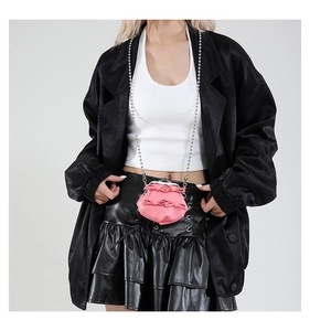 Detail der rosa Schleifen-Umhängetasche mit Perlenkette und Vintage-Verschluss am Modell