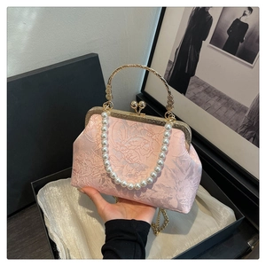 Close-up of pink jacquard evening bag with pearl handle and ornate gold metal frame