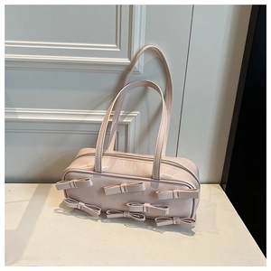 Close-up of pink patent leather handbag featuring six decorative 3D bows and silver zipper