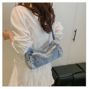 Détail du sac cylindre en jean bleu vintage avec pendentif perle porté à l'épaule