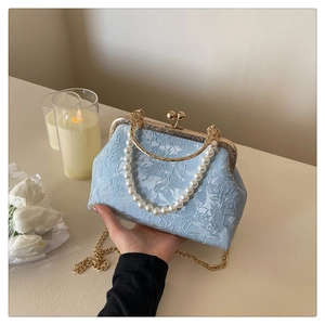 Detail of light blue floral jacquard bag with pearl handle and ornate gold frame