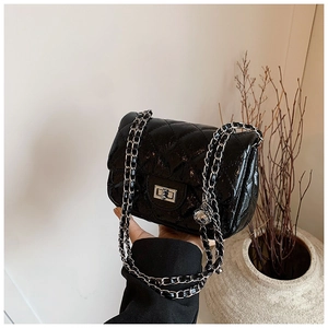 Détail du sac en cuir verni matelassé noir avec fermoir rotatif argenté et chaîne