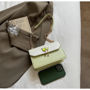 Détail du sac à bandoulière en cuir vert et blanc avec chaîne dorée et boucle chat