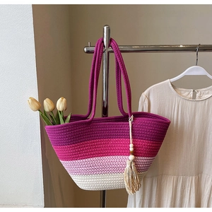 Close-up of vibrant gradient woven straw tote bag with tassels and tulip decoration