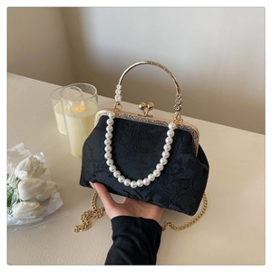 Macro detail of black floral jacquard evening bag with pearl handle and golden clasp