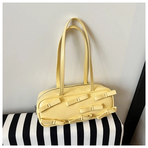 Detail of cream yellow patent leather bag featuring elegant 3D bow accents and slim straps