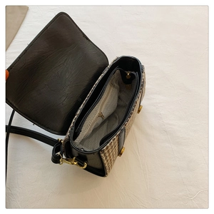 Detail of checkered tweed crossbody bag showing black leather trim and internal zip pocket