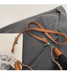 Detail of adjustable shoulder strap with silver metal chain on a brown textured handbag