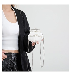 Close-up of mini white bow bag with pebble leather texture and silver ball chain strap