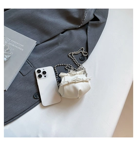 Mini white bow bag with lychee texture and silver chain strap shown next to a smartphone