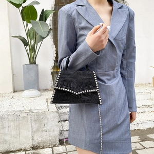 Elegant black rhinestone handbag with silver chain strap shown in a modern outdoor setting