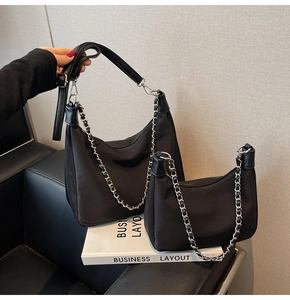 Detail of large and small black nylon shoulder bags with silver chain and leather trim