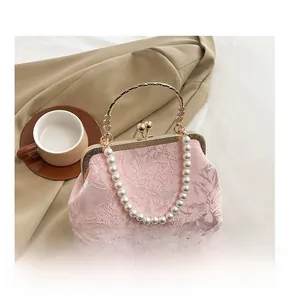 Close-up of pink lace evening bag featuring pearl handle and golden ball clasp closure