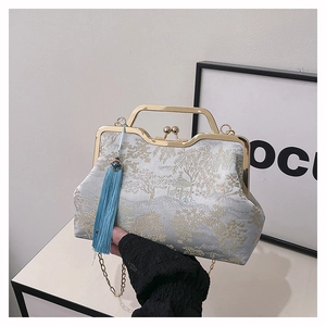 Detail of embroidered cheongsam evening bag with golden handle and blue tassel charm