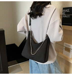 Detail view of large black nylon shoulder bag with silver chain and leather strap