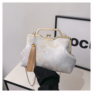 Detail of silver silk embroidered handbag featuring vintage pearl clasp and gold handle